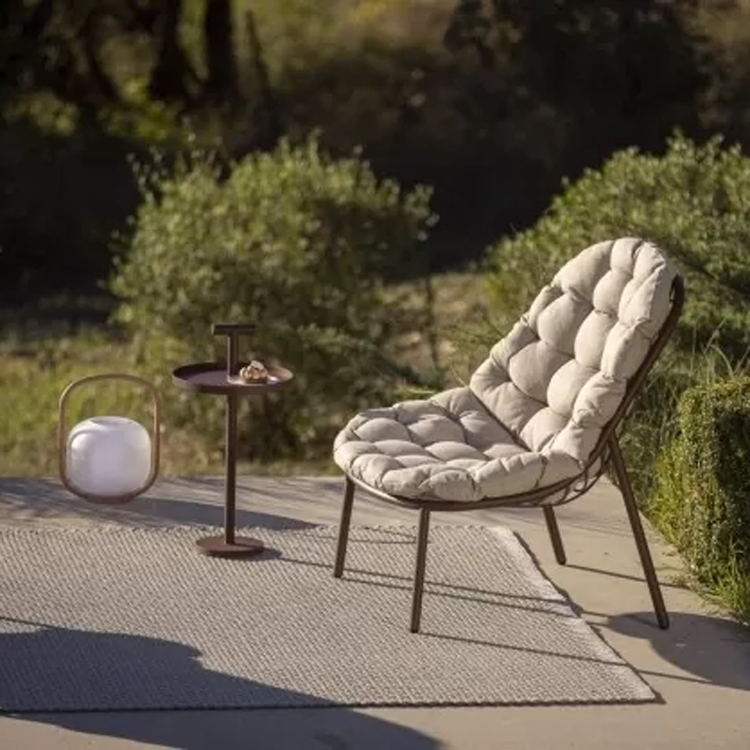 chaise longue avec table d'appoint marron sur tapis tissé vue latérale dans un environnement vert | albus