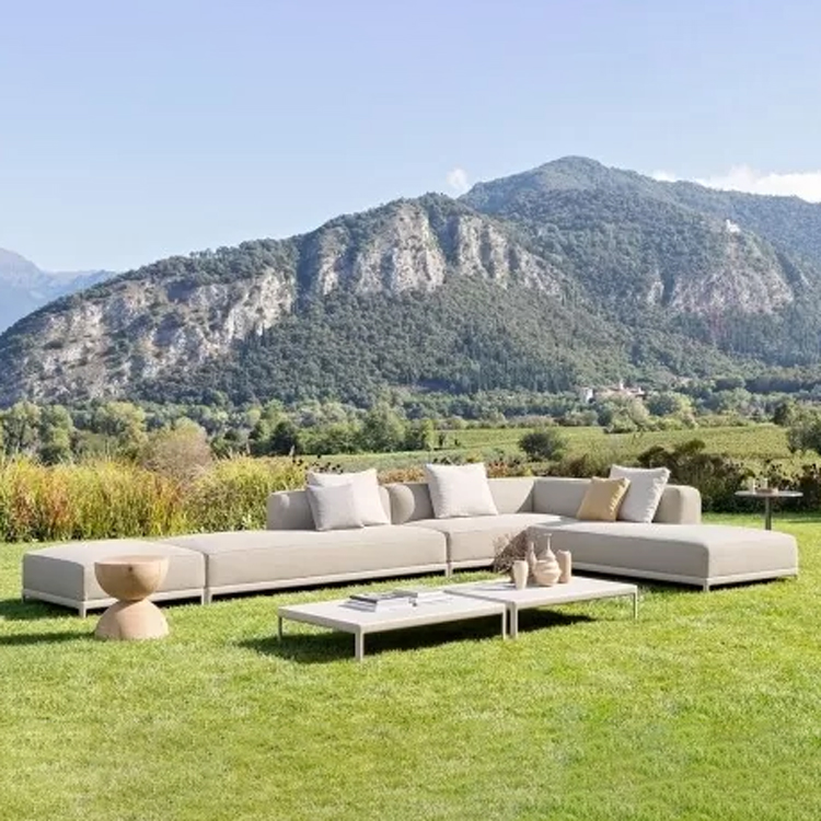 beige stoffen loungeset met tafel op het gras met berglandschap