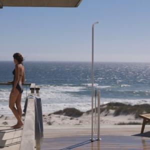 vrouw in zwempak op terras naast vola fs 3 douchekraan