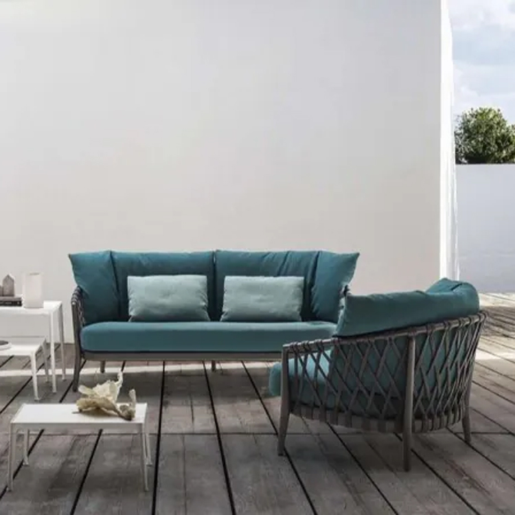 blauwe loungeset met loungestoel en witte tafeltjes voorzijde op een houten platform voor een witte muur