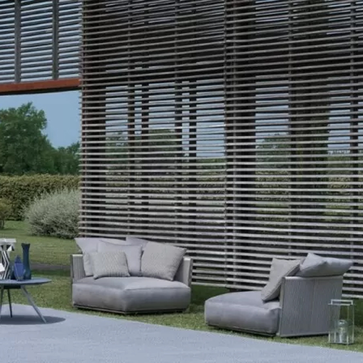 outdoor grijze loungeset met grijze tafel op gras langs een grote muur