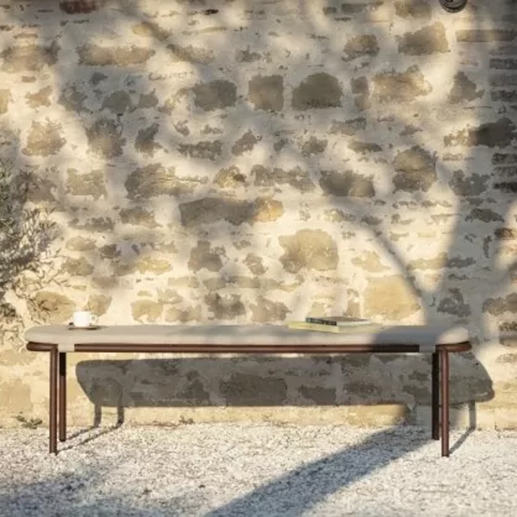 banc d'étourneaux beige sur des galets avec un mur de pierre en arrière-plan