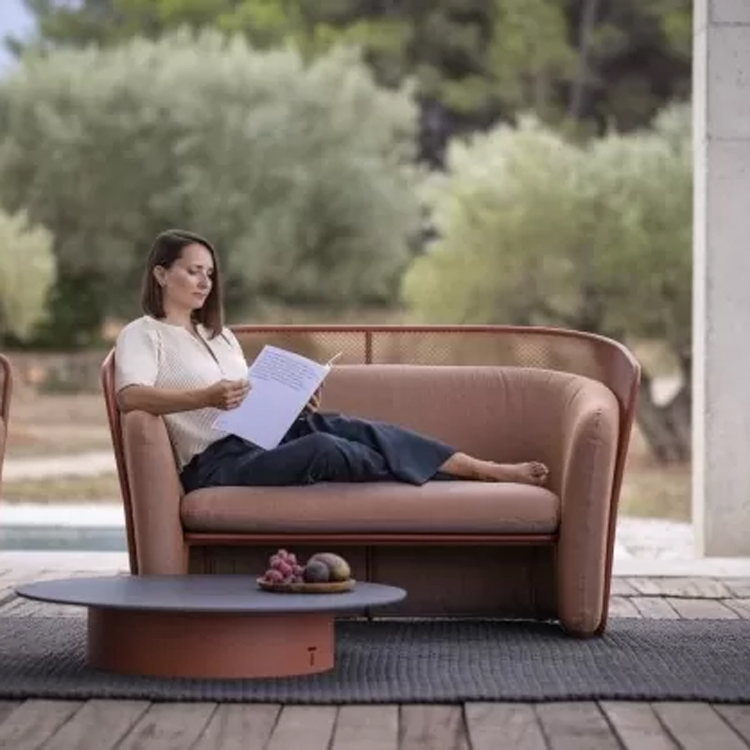 vrouw leest in een oranje loungezetel met tafel voorzijde
