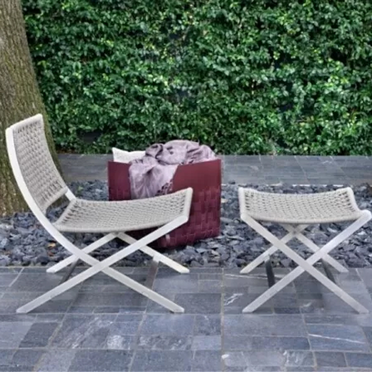 outdoor beige loungestoel op stenen vloer met mand met dekens zijaanzicht