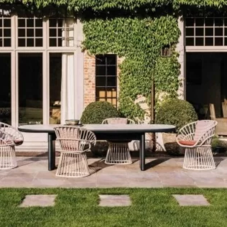 tuintafel met stoelen voorzijde langs een groot huis met begroeiing